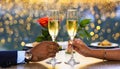 Close-up of two champagne glasses and a couple\'s hands at a restaurant table. romantic duo