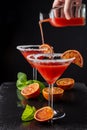 Close-up of two cocktail glasses with unfocused bottle serving blood orange martini, half orange and mint, on black background Royalty Free Stock Photo