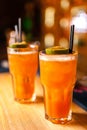 Close-up of two colorful orange cocktails with lime and brown sugar in bar.