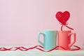 Close up of Two cups and heartshaped lolipop or hard candy on table. pink background. Place for text. copyspace. St. Valentine`s