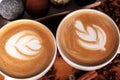 Two cappuccino cups with latte-art on a wooden table with scattered coffee beans and cakes. Joy with a Cup of coffee Royalty Free Stock Photo