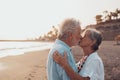 Close up of two cute and happy seniors having fun and enjoying together a sunset day at the beach. Mature couple in love kissing Royalty Free Stock Photo