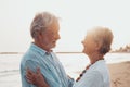 Close up of two cute and happy seniors having fun and enjoying together a sunset day at the beach. Mature couple in love looking Royalty Free Stock Photo