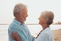 Close up of two cute and happy seniors having fun and enjoying together a sunset day at the beach. Mature couple in love looking Royalty Free Stock Photo