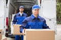 Close-up Of Two Delivery Men Carrying Cardboard Box Royalty Free Stock Photo