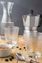 Close-up of two empty glasses, spoon, coffee beans, brown sugar with gray coffee pot and bottle of water, with selective focus, on Royalty Free Stock Photo