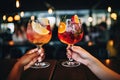 Close up of two female hands holding glasses of cocktails in the bar, Cropped image of female friends clinking glasses with