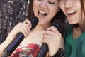 Close-up of two friends holding microphones and singing together at karaoke Royalty Free Stock Photo