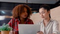 Close-up two girls who are sitting for an exam and explaining each other doing practice exam, in front laptop computer Royalty Free Stock Photo