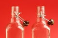 Close up of two glass empty open alcohol bottles over red background