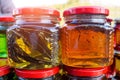 Close-up of two glass jars honey with leaves in market