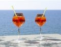 Close up of two glasses of chilled cocktail drinks with straws and ice cubes on a table a sunny day