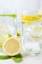 Close-up of two glasses of ice water, half a lemon and mint leaves, on white table Royalty Free Stock Photo