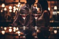 Close up of two glasses of red wine on a table in a restaurant. Happy young couple in the background Royalty Free Stock Photo