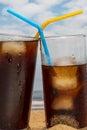 Close-up of two glasses of soda with ice and straws on the beach with blue sky in Tenerife, Canary Islands