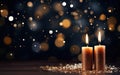 Close up of two golden burning candles on the wooden table with sparkling glitter. Blurred Christmas light background