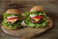 Close-up. Two hamburger with beef cutlet, with cheese, pickles, tomatoes, onions, lettuce on a wooden rustic background. Royalty Free Stock Photo