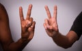 Close up of two hands, african and caucasian, making the Victory sign, concept of integration, diversity and multi ethnicity