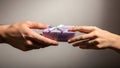 close up of two hands exchanging a small lavender gift box with white ribbon over plain background Royalty Free Stock Photo