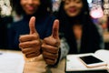 Close up of two hands hold big thumb up. Young african women smile. They have study materials and phone at table. Royalty Free Stock Photo