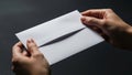 A close-up of two hands holding a plain white envelope against a dark background Royalty Free Stock Photo