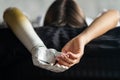 Close up two hands of woman with disability bionic arm on black bed at home, person lost her arm, disabled cyborg girl