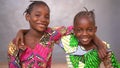 Close Up Of Two Little African Girls in Beautiful Dresses Smiling Into The Camera