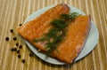 Close-up of two large pieces of lightly salted trout fillet on a blue plate, allspice and a sprig of dill Royalty Free Stock Photo