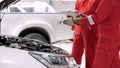 Close up. Two male mechanics in a garage front of a car with the hood open. Wear work clothes in the garage to protect yourself