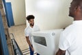 Young Movers Carrying Cabinet While Climbing Steps