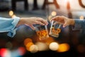 Close-up of two men clinking whiskey glasses drinks alcoholic beverage together while at bar counter in the pub after work on Royalty Free Stock Photo