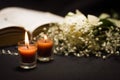 Close up of two orange candles with a blurred rosary beads over a holy bible and small flowers, black background Royalty Free Stock Photo