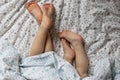 Close-up of two pairs of toddler girls feet on the bed under the blanket. Light blue and beige tones Royalty Free Stock Photo