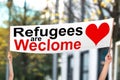 Two People Holding Refugees Are Welcome Banner