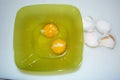 Close up of two raw eggs in a green plastic bowl and eggshells Royalty Free Stock Photo