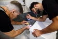 Close up of two repairmen, workers in uniform working, fixing washing mashine using screwdriver and flashlight in the