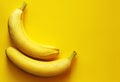 Two bananas lying side by side on a yellow background