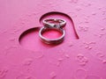 Close up two silver rings on a red heart-shaped card over red paper background with copy space. Royalty Free Stock Photo