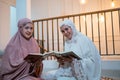 close up of two smiling hijabi girls reciting the Quran