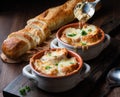 Close up of two soup crocks filled with French onion soup and a spoon scooping some out of one.