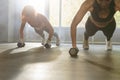 Close up of two sporty women doing push-up exercise with dumbbell. Strong females doing workout