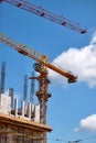 Close-up of two tower cranes working against the backdrop of a new building and blue sky, selective focus Royalty Free Stock Photo