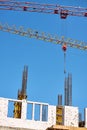 Close-up of two tower cranes working against the backdrop of a new building and blue sky, selective focus Royalty Free Stock Photo
