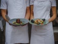 Couple of waiters holding plates. Waiter and waitress serving food on a blurred background. Classic restaurant concept. Royalty Free Stock Photo