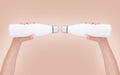 Close-up of two white eco bottles in female hands on light brown background. Royalty Free Stock Photo