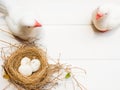 close up of two white pigeon statue bird and bird nest with three white stone on white background and copy space