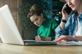 Close up.Two young business women sitting in office at table and work together.On table laptop and paper charts. Royalty Free Stock Photo