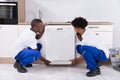 Two Handy Men Fixing The Dishwasher In The Kitchen Royalty Free Stock Photo