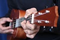 Close up ukulele in musician hands, left hand view