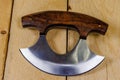 Close up of a Ulu knife with a wood handle on pine boards.